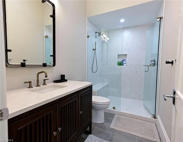 a bathroom with a sink a toilet a mirror and shower