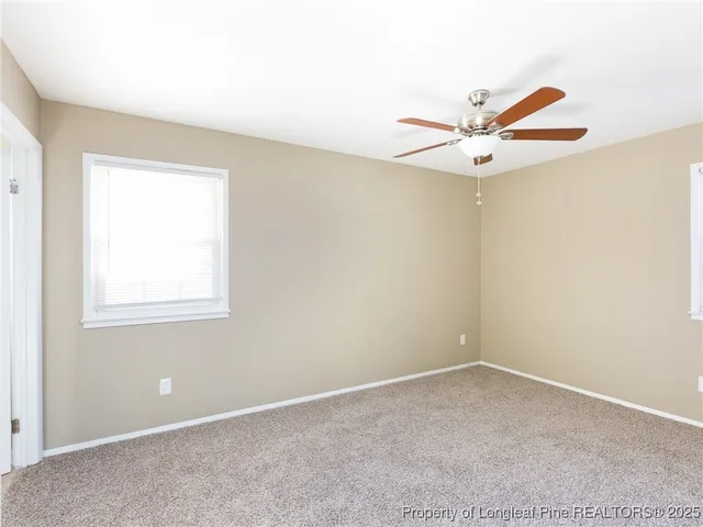 an empty room with a window and a ceiling fan