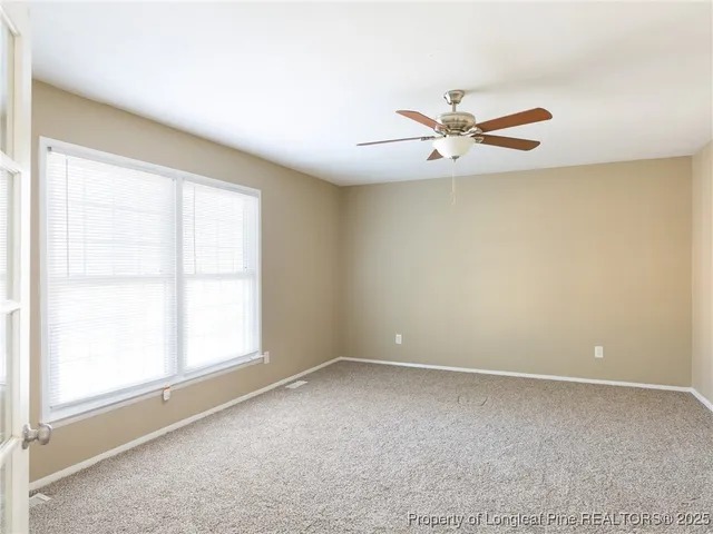 an empty room with windows and fan