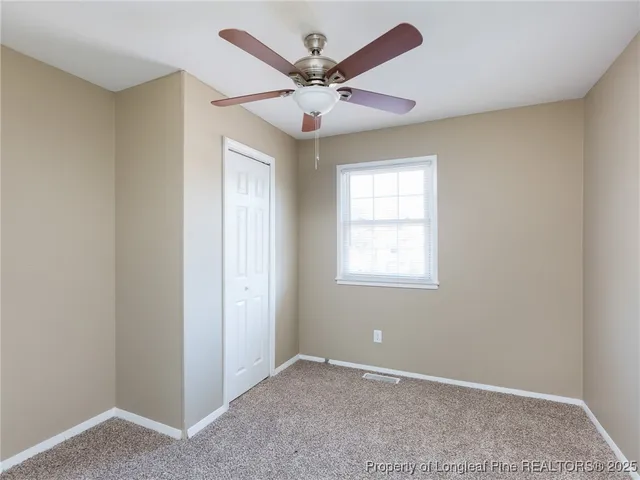 an empty room with windows and ceiling fan