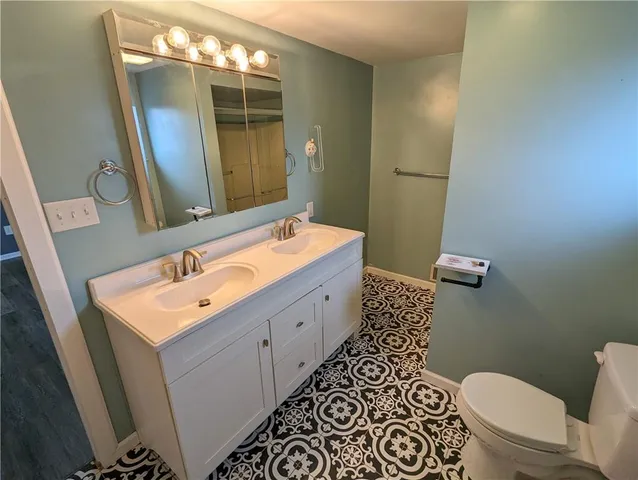 a bathroom with a double vanity sink mirror and toilet
