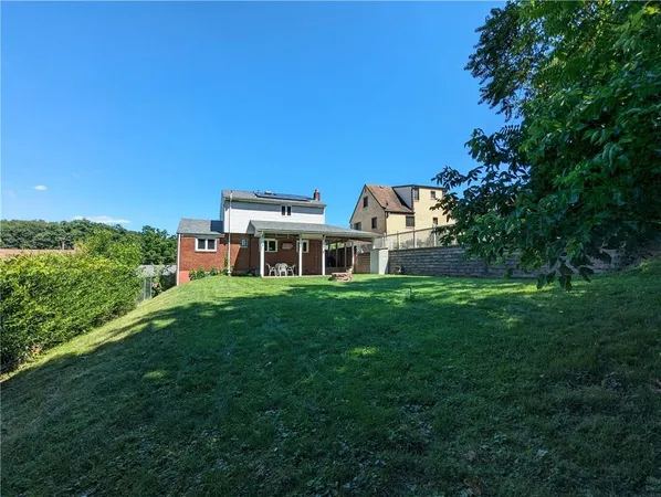 a view of a brick house with a big yard and large trees