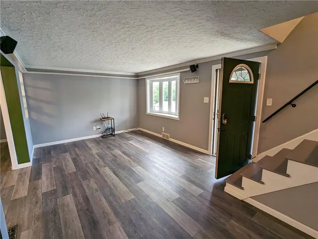 a view of an empty room with window and wooden floor