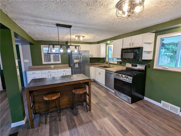 a kitchen with a sink appliances and wooden floor