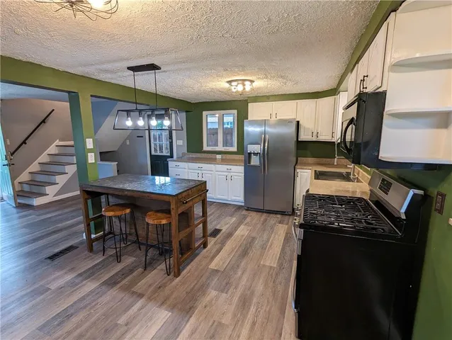 a kitchen with stainless steel appliances granite countertop a refrigerator a stove and a wooden floors
