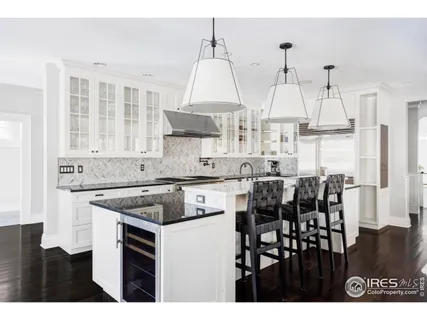 a kitchen with stainless steel appliances granite countertop a stove a sink dishwasher and white cabinets with wooden floor