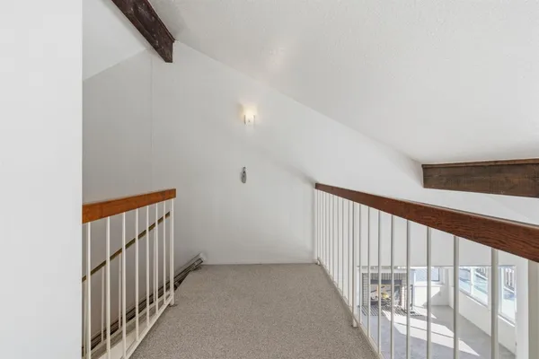 a view of an empty room with wooden floor and windows
