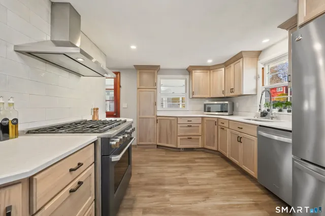 a kitchen with stainless steel appliances granite countertop a stove a sink dishwasher and a refrigerator