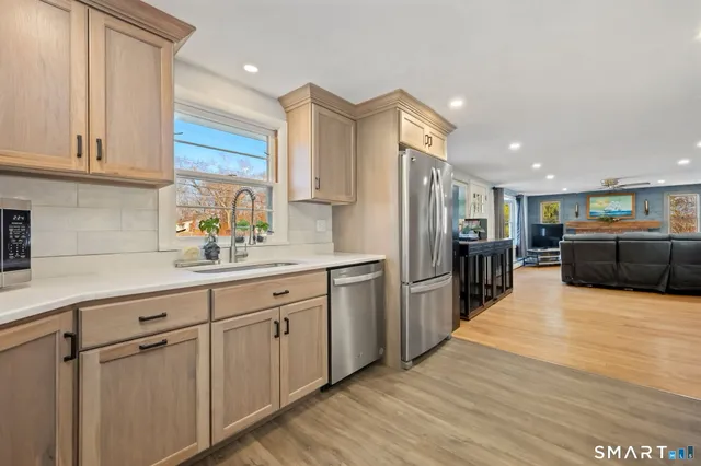a kitchen with stainless steel appliances kitchen island granite countertop a refrigerator and a sink