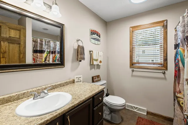 a bathroom with a granite countertop toilet a sink and a mirror
