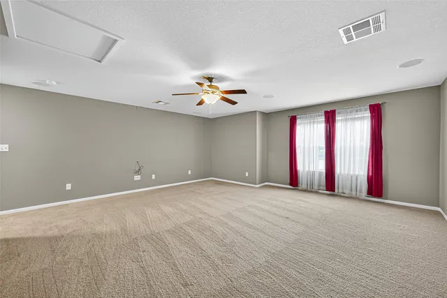an empty room with a chandelier fan and windows