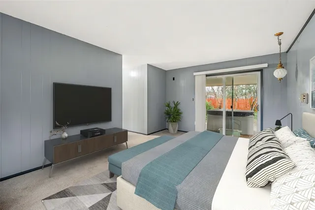 a bedroom with a bed and a flat tv screen on dresser