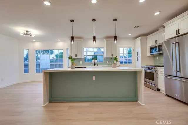a kitchen with stainless steel appliances kitchen island granite countertop a sink stove and refrigerator