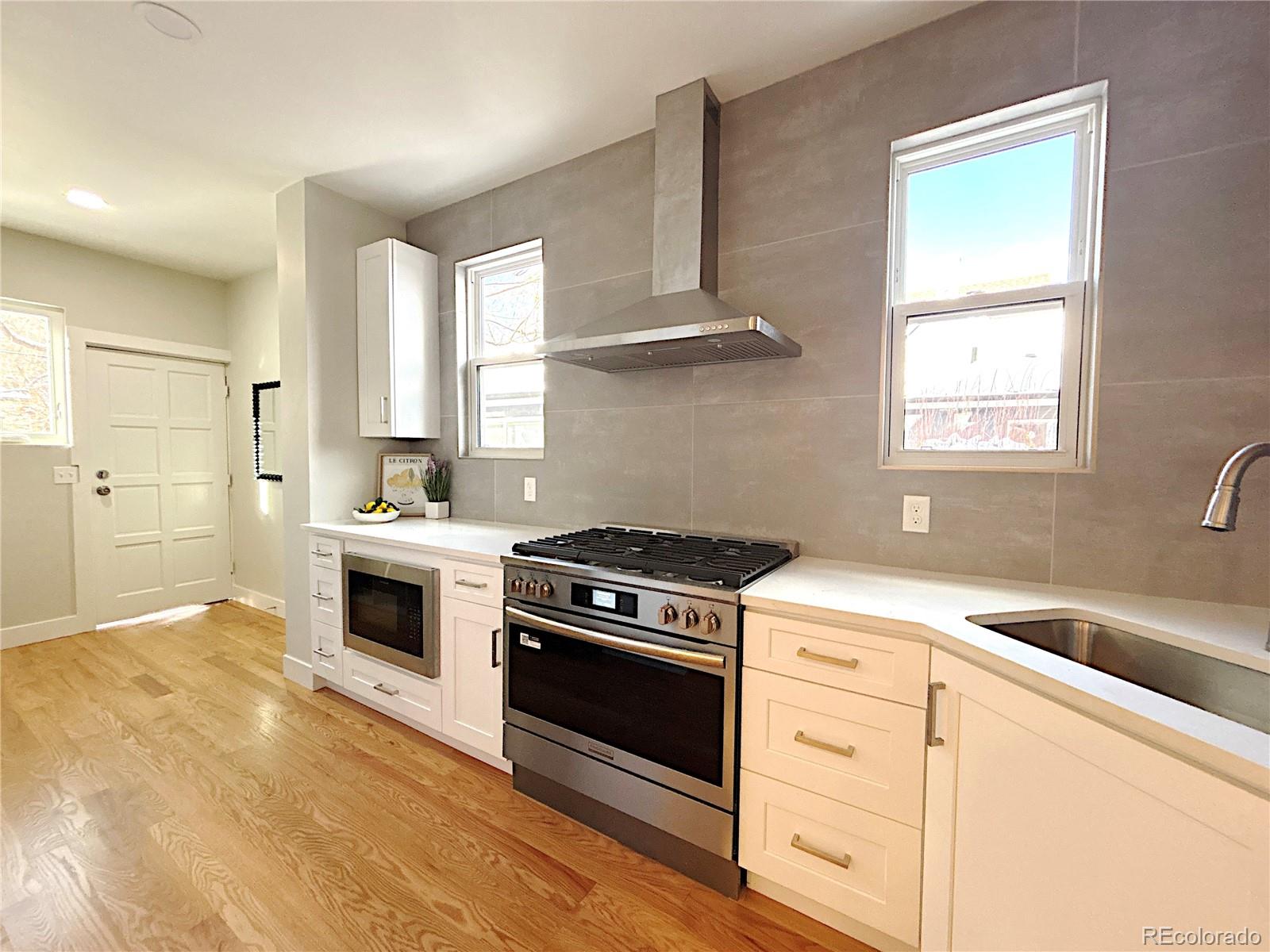 1129 Fillmore Street Denver, CO 80206 - Photo 6 of 32 a kitchen with white cabinets and appliances