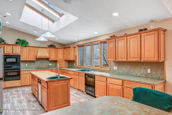 a large kitchen with stainless steel appliances granite countertop a refrigerator a sink dishwasher a stove and white countertops with wooden floor