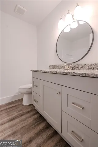 a bathroom with a granite countertop toilet and a sink