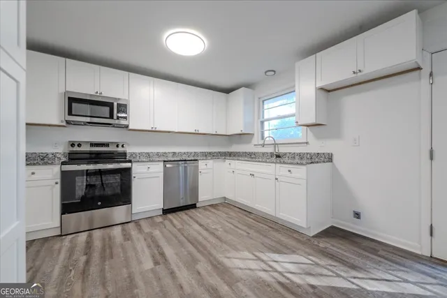 a kitchen with stainless steel appliances granite countertop a stove a sink and a microwave