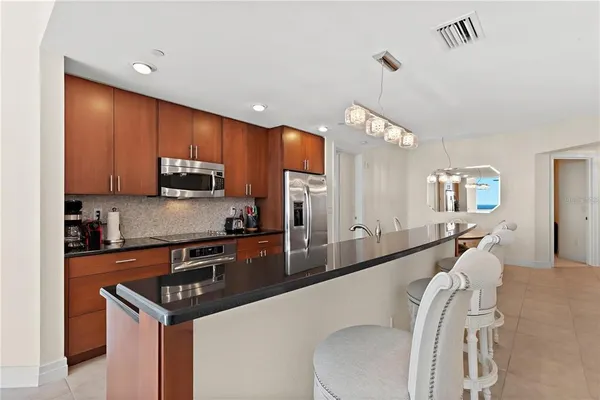 a kitchen with stainless steel appliances a sink a stove a refrigerator cabinets and a dining table