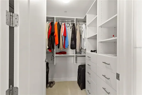 a view of walk in closet with clothes and shoes