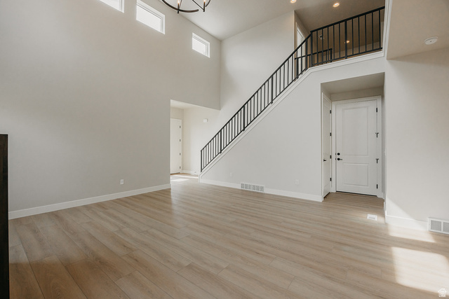 5910 Canyon Rim Road, Unit 619 Lehi, UT 84048 - Photo 38 of 52 Soaring ceilings with transom windows, wood-finish flooring, a two-story staircase with black iron balusters, and a contemporary chandelier