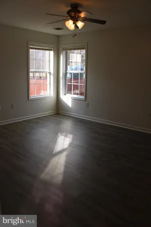 a view of empty room with wooden floor and a window