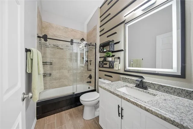 a bathroom with a granite countertop sink toilet a mirror and shower