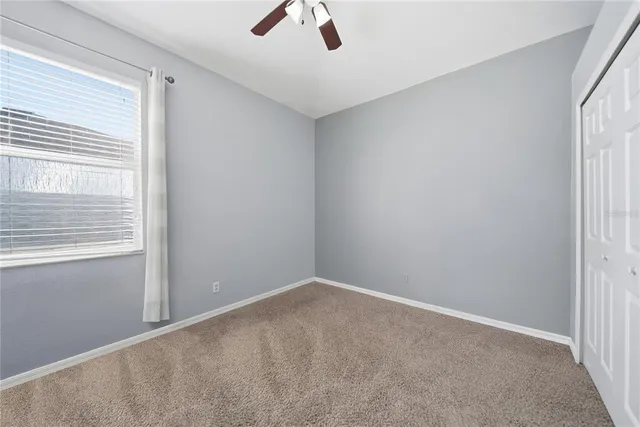 an empty room with a window and a ceiling fan