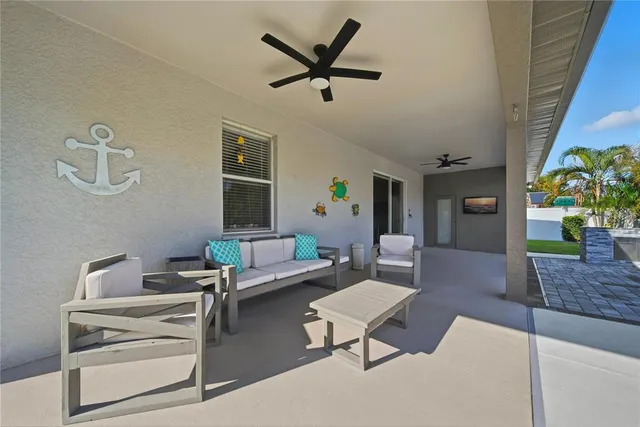 a view of a patio with a table and chairs under an umbrella with palm trees