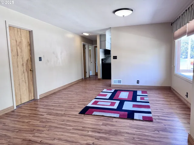 a bedroom with wooden floor and window