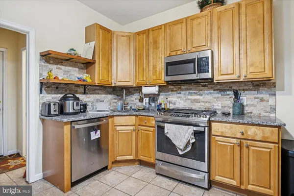 a kitchen with stainless steel appliances granite countertop a stove a sink and a microwave
