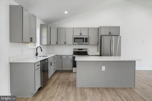a kitchen with a sink dishwasher and a refrigerator with wooden floor