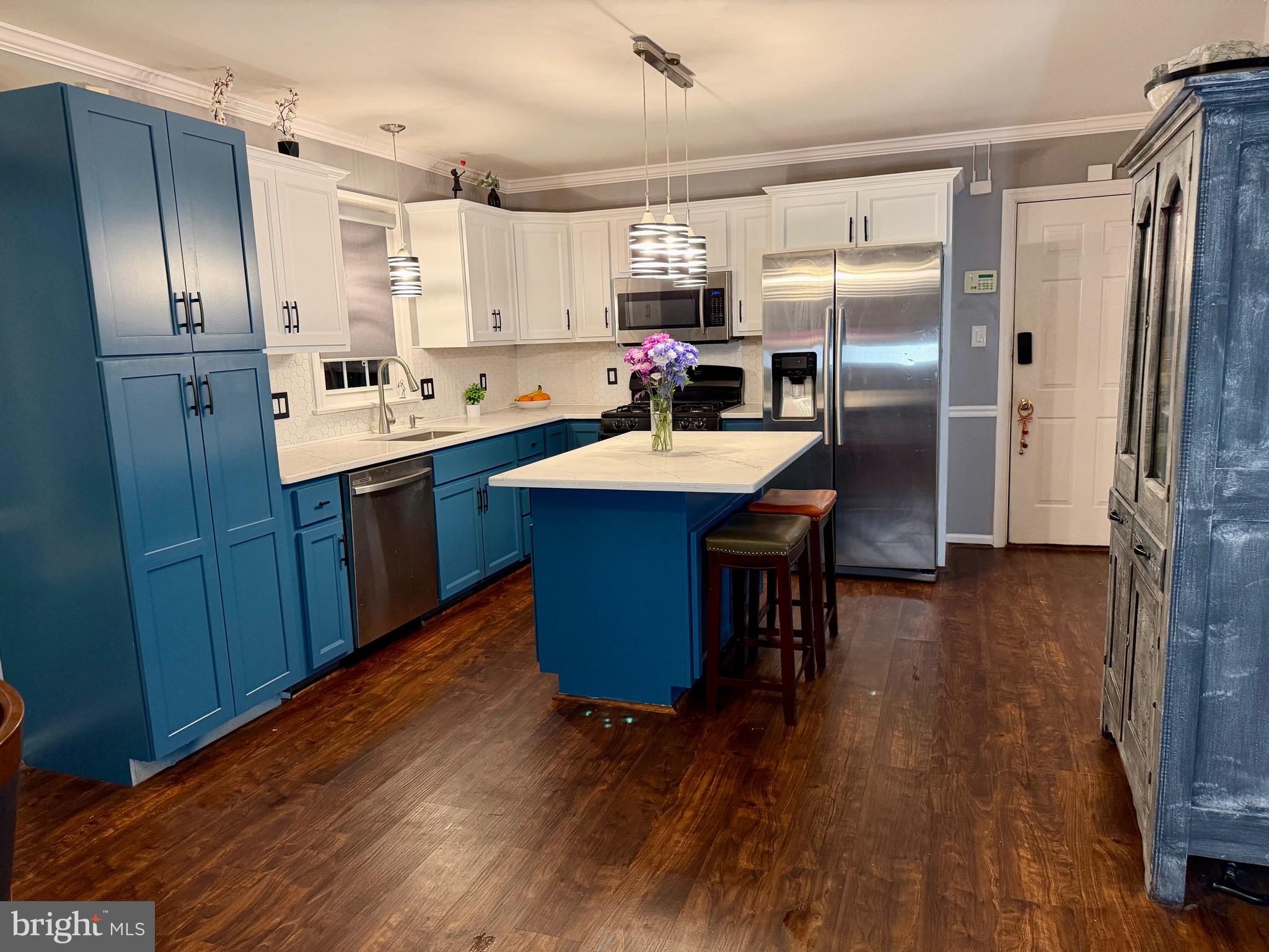 a kitchen with stainless steel appliances granite countertop a refrigerator a sink dishwasher a stove and a refrigerator with wooden floor