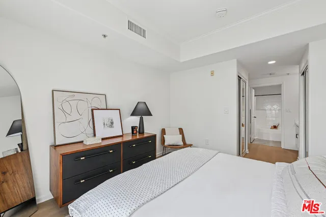 a bedroom with a bed and a flat tv screen on dresser
