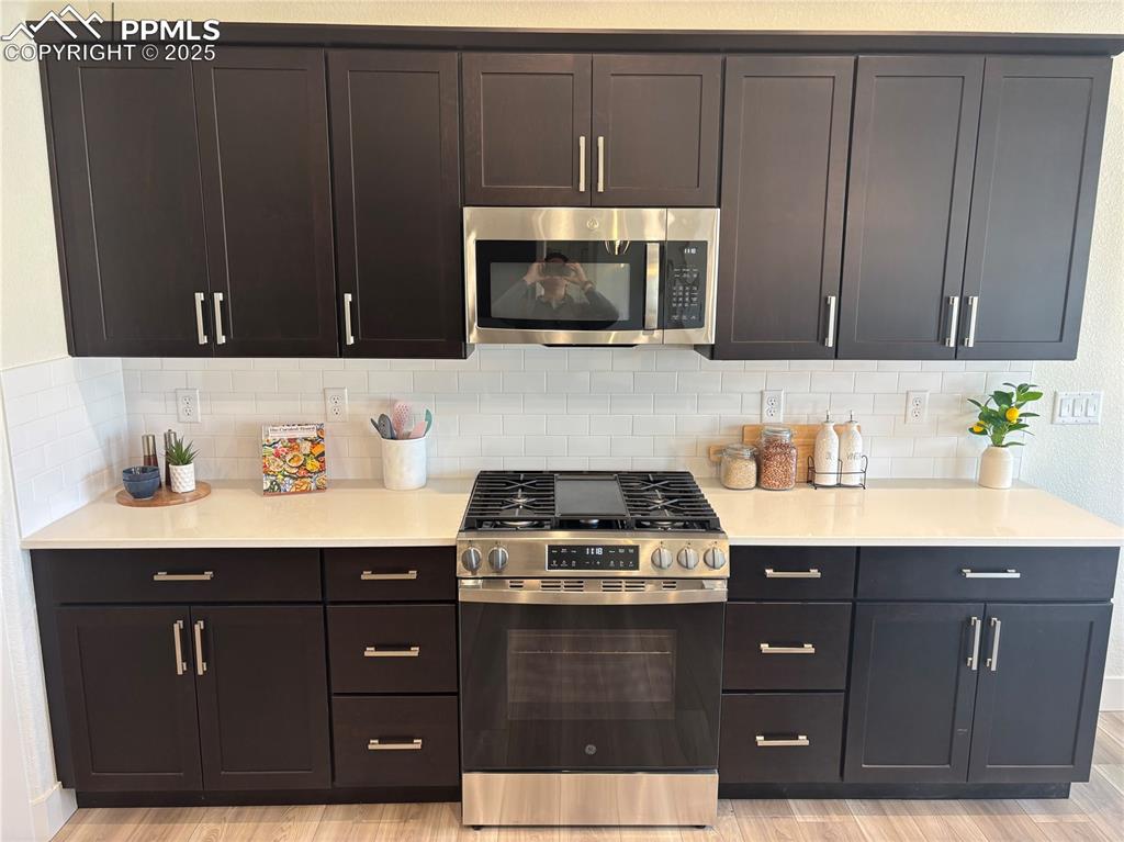 817 Keystone Loop Canon City, CO 81212 - Photo 4 of 19 Kitchen featuring stainless steel appliances, light wood-style floors, light stone countertops, and decorative backsplash