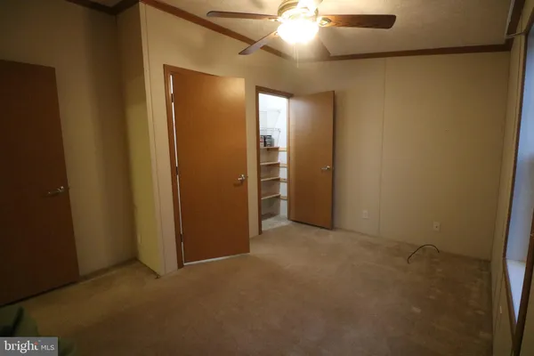 an empty room with closet and a chandelier fan