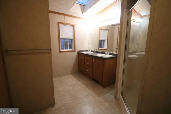 a bathroom with a granite countertop sink a mirror and a refrigerator