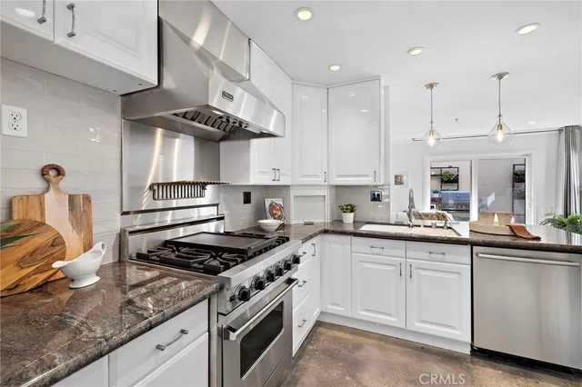a kitchen with stainless steel appliances granite countertop a sink a stove and cabinets