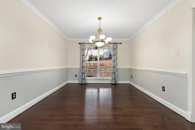 an empty room with wooden floor a ceiling fan and windows