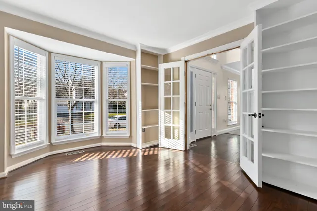 an empty room with wooden floor and windows