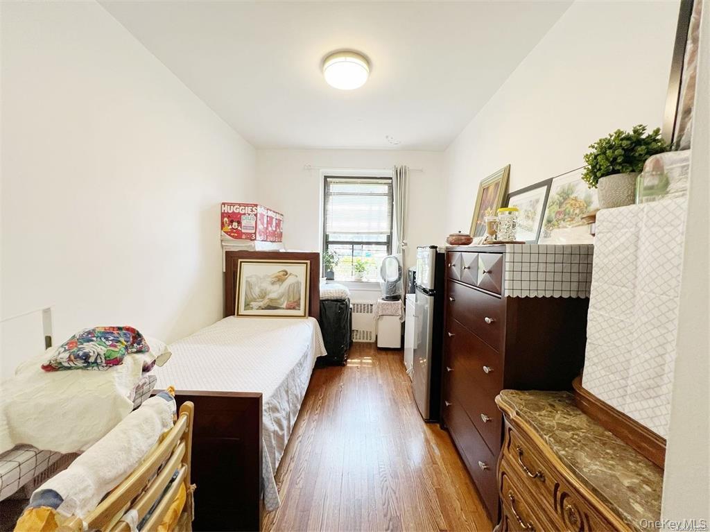 112-19 34th Avenue, Unit F Queens, NY 11368 - Photo 6 of 11 a bedroom with a bed and wooden floor