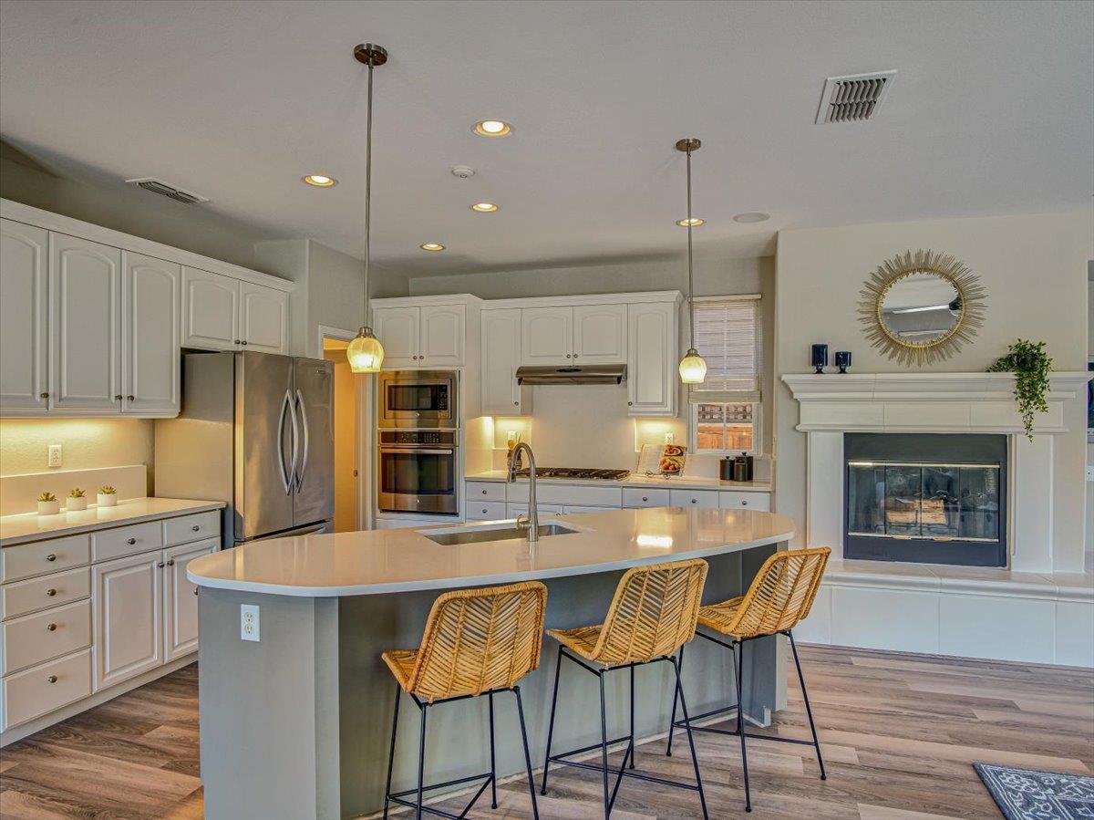 1042 Promenade Street Hercules, CA 94547 - Photo 13 of 60 a kitchen with granite countertop a stove a sink dishwasher a refrigerator and a fireplace with wooden floor