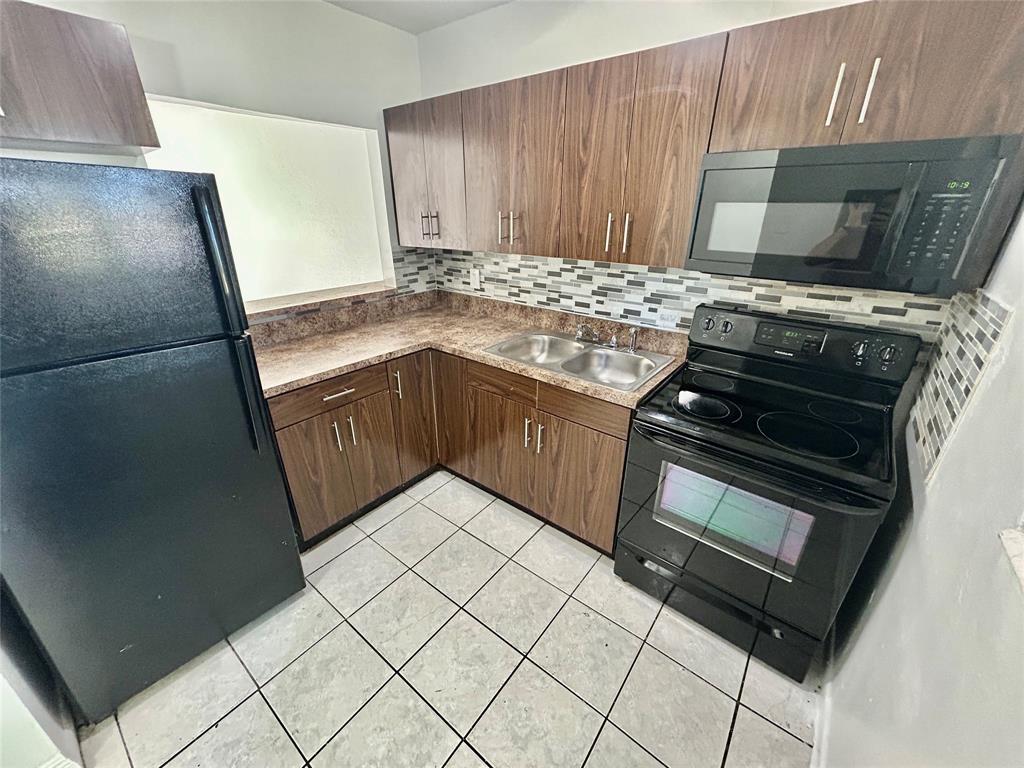 2252 Northwest 183rd Street, Unit 4 Miami Gardens, FL 33056 - Photo 11 of 15 a kitchen with granite countertop a refrigerator stove and cabinets