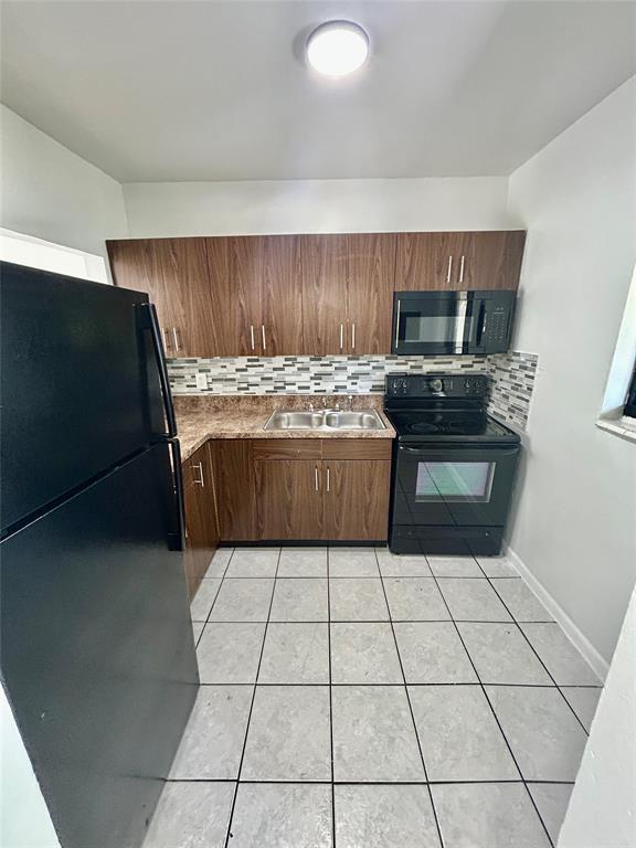 2252 Northwest 183rd Street, Unit 4 Miami Gardens, FL 33056 - Photo 12 of 15 a kitchen with kitchen island granite countertop a stove a sink and a microwave