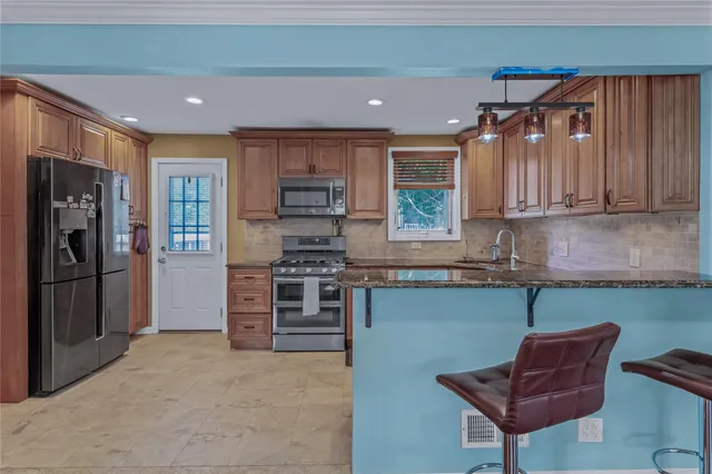 a kitchen with stainless steel appliances granite countertop a refrigerator and a stove top oven