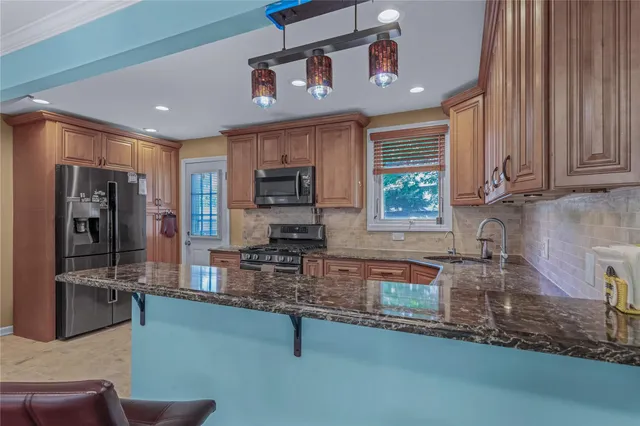 a kitchen with stainless steel appliances granite countertop a sink a stove cabinets and a refrigerator