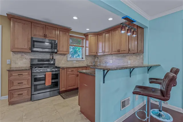 a kitchen with stainless steel appliances granite countertop a stove a sink and a microwave