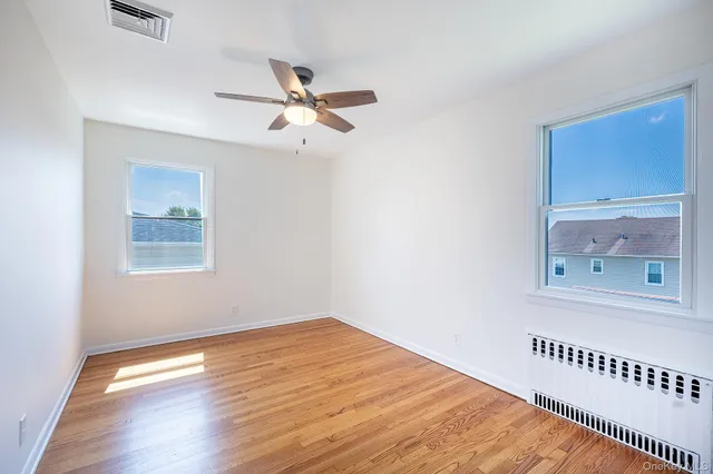 a view of an empty room with a window and wooden floor