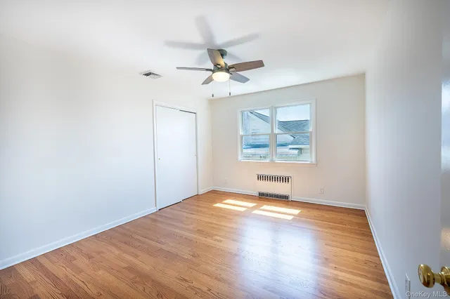 an empty room with wooden floor chandelier fan and windows