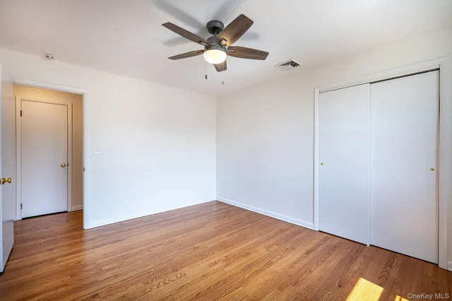 an empty room with wooden floor and a ceiling fan