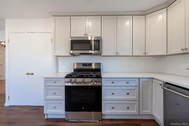 a kitchen with stainless steel appliances white cabinets and a stove a refrigerator with wooden floors